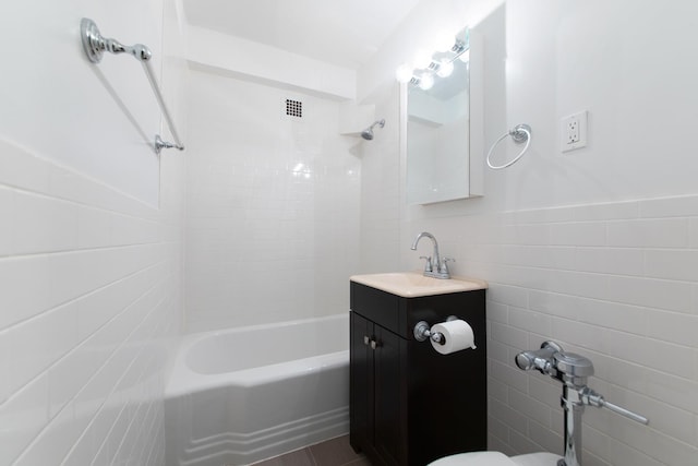 bathroom featuring  shower combination, a wainscoted wall, tile walls, and vanity