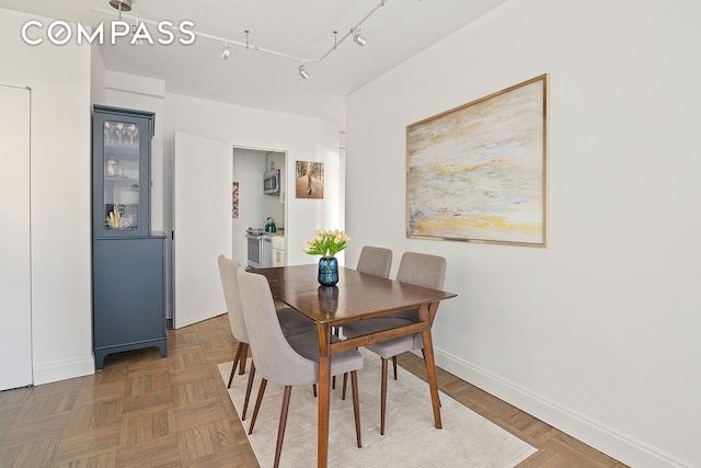 dining space with track lighting and baseboards