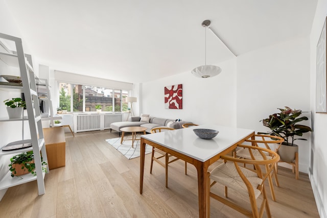 dining space featuring radiator heating unit and light wood-style flooring