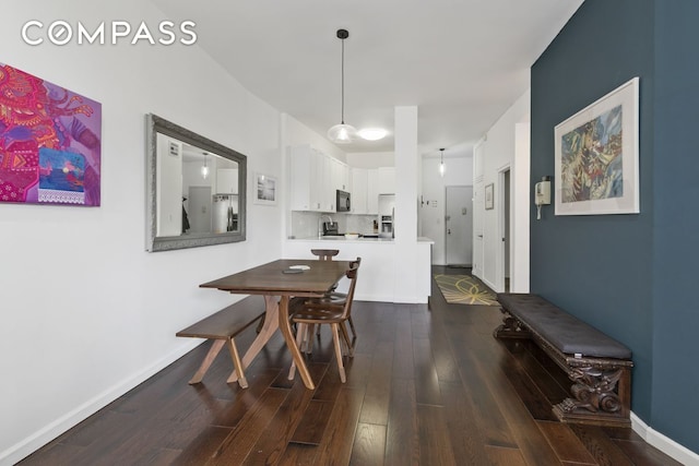 dining space with baseboards and dark wood finished floors