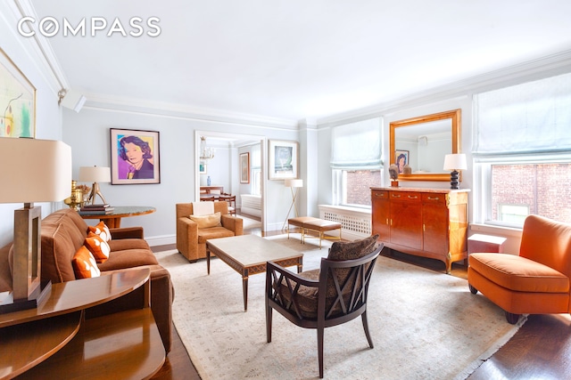 living area with baseboards, crown molding, and radiator heating unit