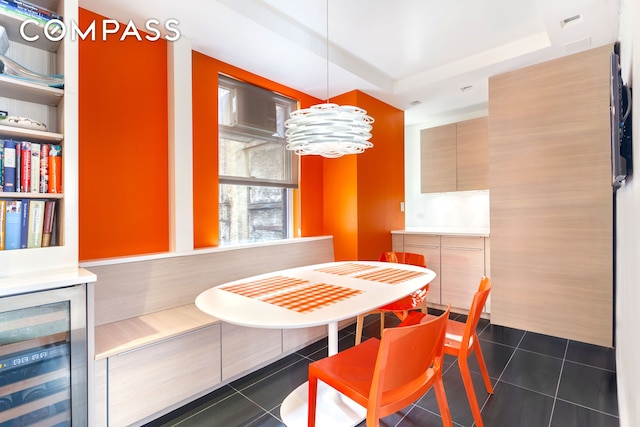 8 E 96th St Unit 7C, New York City, NY 10128 - dining room featuring wine cooler, dark tile patterned floors, a chandelier, and a raised ceiling
