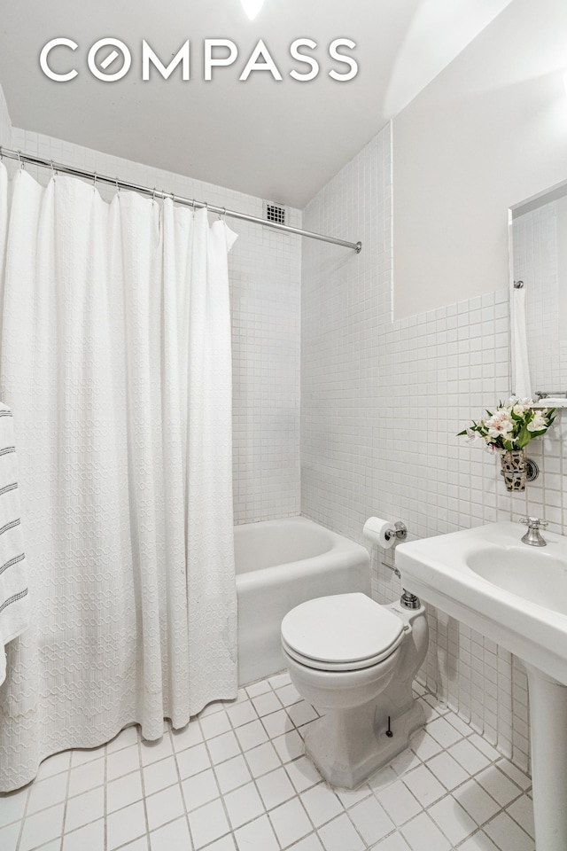 full bathroom with toilet, tile patterned floors, tile walls, and shower / tub combo with curtain