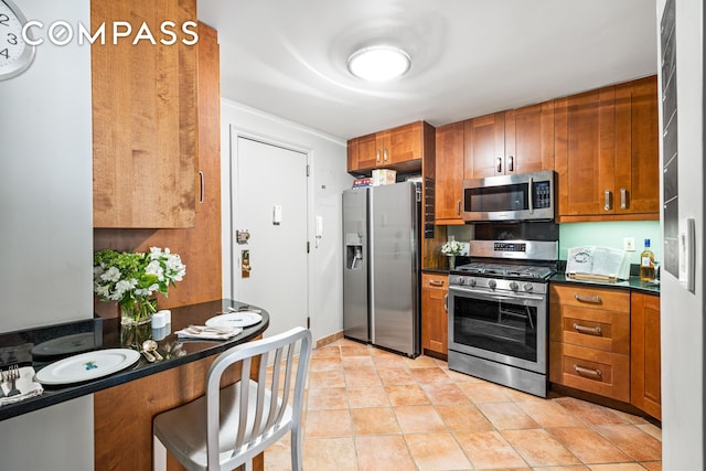 kitchen featuring appliances with stainless steel finishes, dark countertops, and brown cabinets