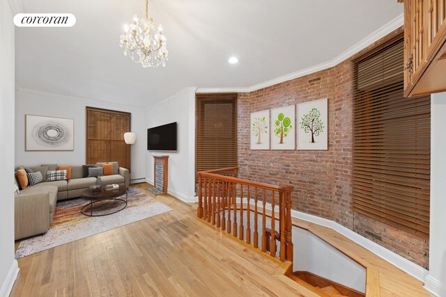 5 W 107th St Unit 1A, New York City, NY 10025 - living room featuring brick wall, baseboards, crown molding, wood finished floors, and a chandelier