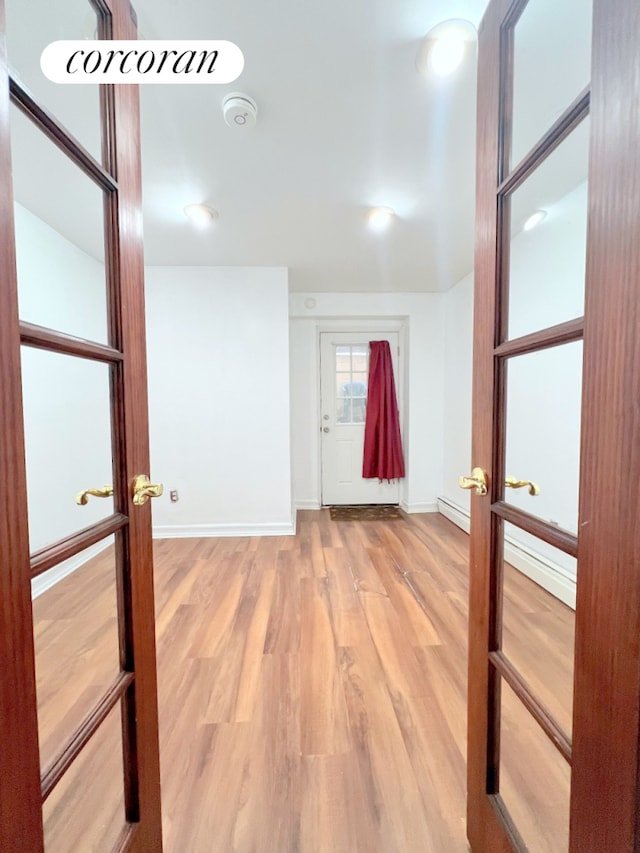 hall featuring wood finished floors, baseboards, and french doors