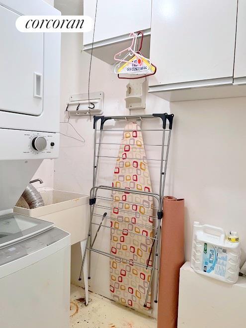 clothes washing area with stacked washer / dryer and cabinet space