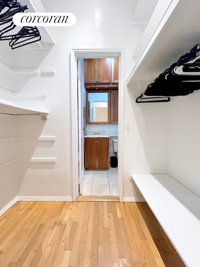 walk in closet with light wood-style floors