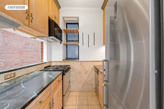 5 W 107th St Unit 1A, New York City, NY 10025 - kitchen with appliances with stainless steel finishes, a wainscoted wall, tile walls, light tile patterned floors, and brick wall