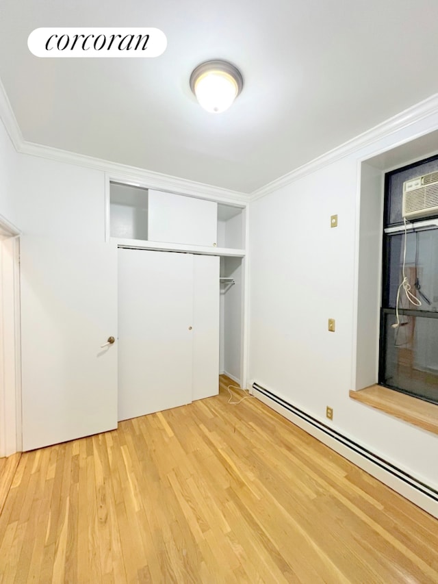 unfurnished bedroom with a baseboard radiator, ornamental molding, light wood-style floors, a closet, and a wall mounted air conditioner