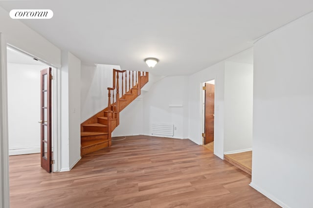 interior space featuring light wood-style floors, stairway, and baseboards