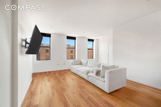 unfurnished living room with baseboards and light wood-type flooring