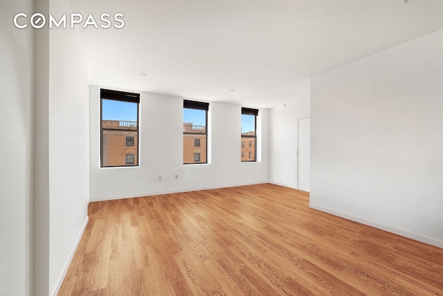 unfurnished room with baseboards and light wood finished floors