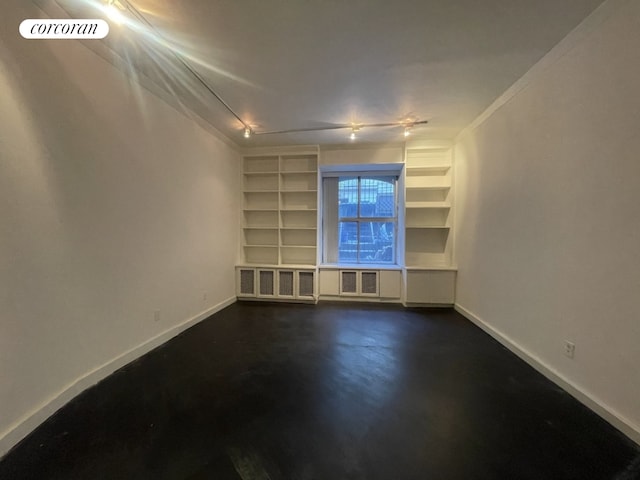 empty room with built in shelves, visible vents, concrete flooring, and baseboards