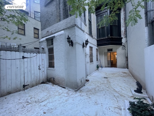 view of side of home featuring a patio, brick siding, and fence