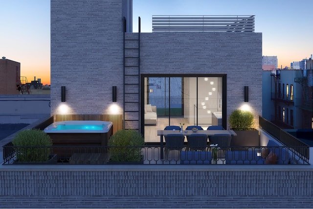 303 W 113th St Ph, Ph, New York City, NY 10026 - back of property at dusk featuring a balcony, an outdoor hot tub, brick siding, and a city view