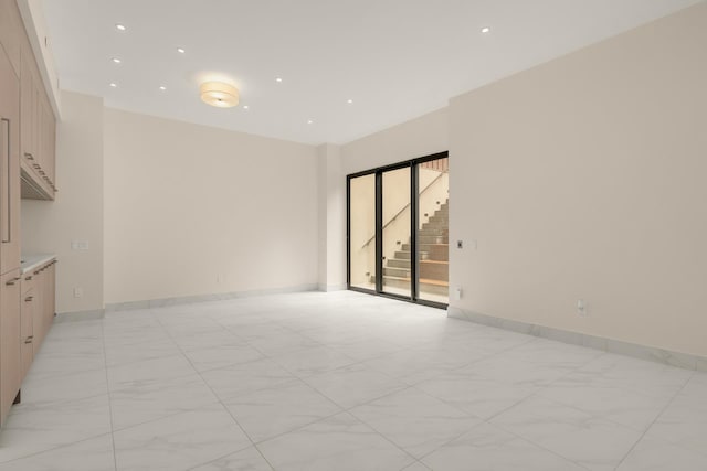 empty room with recessed lighting, marble finish floor, baseboards, and stairs