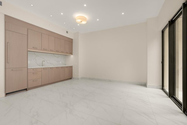 kitchen with marble finish floor, baseboards, light countertops, and backsplash