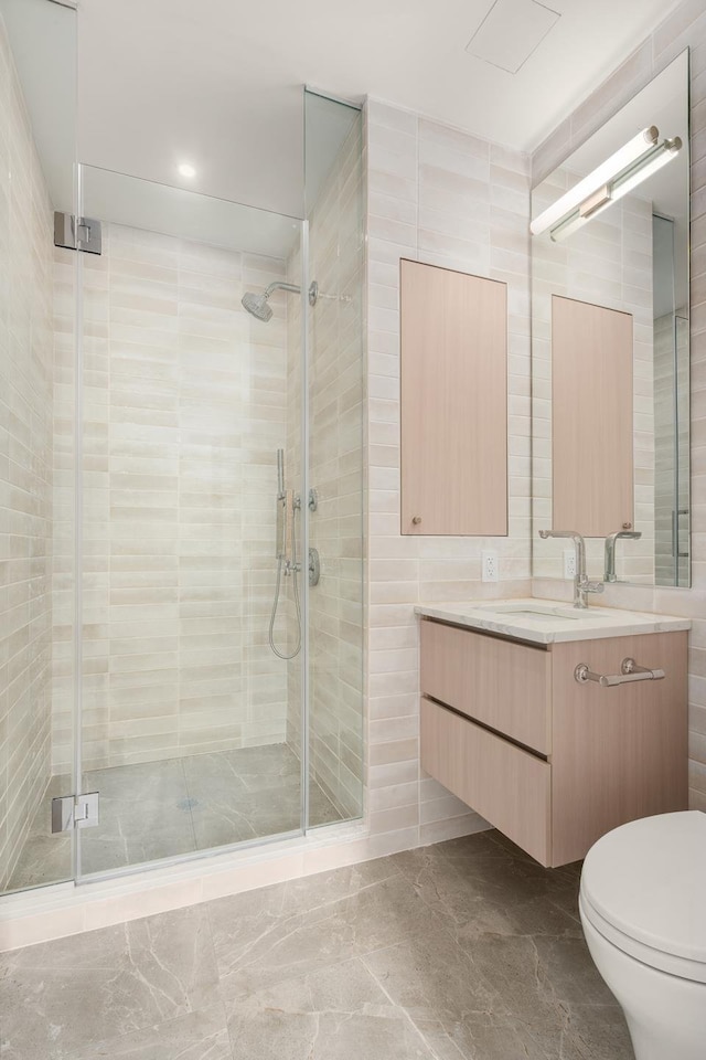 bathroom featuring toilet, tile walls, a shower stall, and vanity