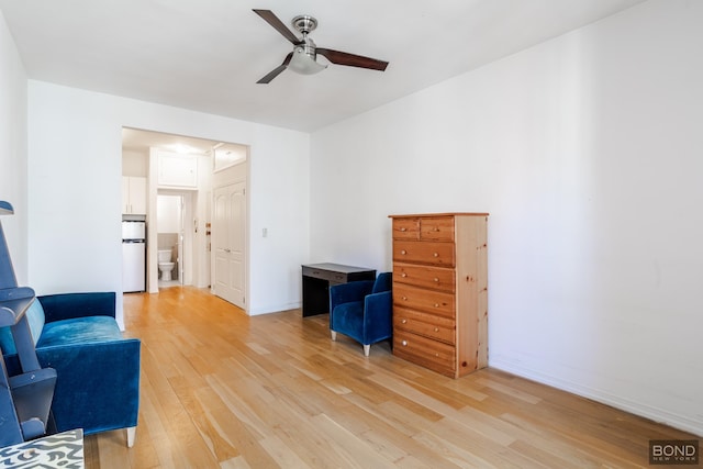 living area featuring light wood-style flooring, baseboards, and a ceiling fan