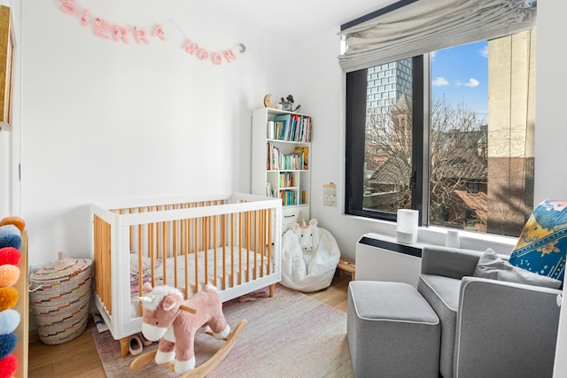 bedroom featuring a nursery area and wood finished floors