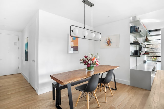 dining area with light wood-style flooring, baseboards, and stairs