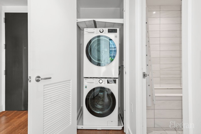 washroom featuring stacked washer / dryer, laundry area, and wood finished floors