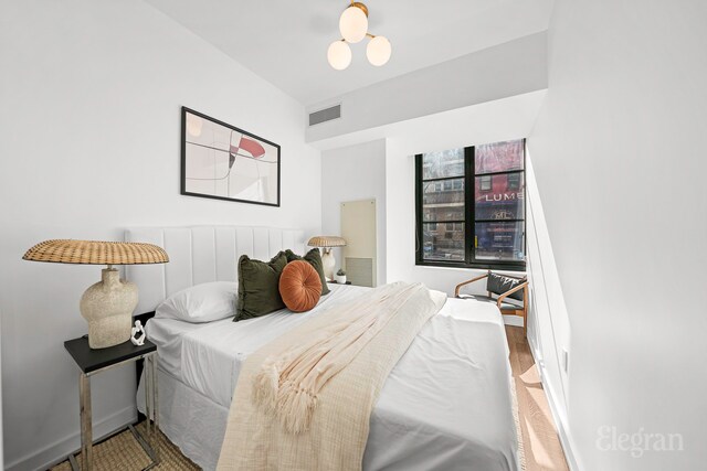 261 W 25th St Unit 1-C, New York City, NY 10001 - bedroom featuring baseboards, a notable chandelier, and wood finished floors