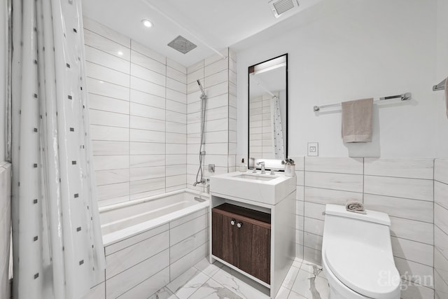 bathroom with visible vents, vanity, tile walls, marble finish floor, and tiled shower / bath