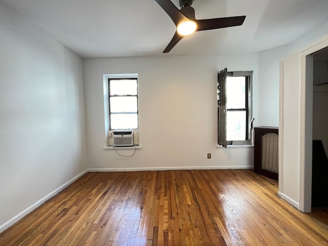 unfurnished bedroom featuring cooling unit, baseboards, and hardwood / wood-style flooring