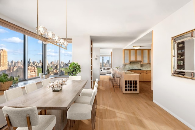 dining space with light wood finished floors, a notable chandelier, baseboards, and a city view