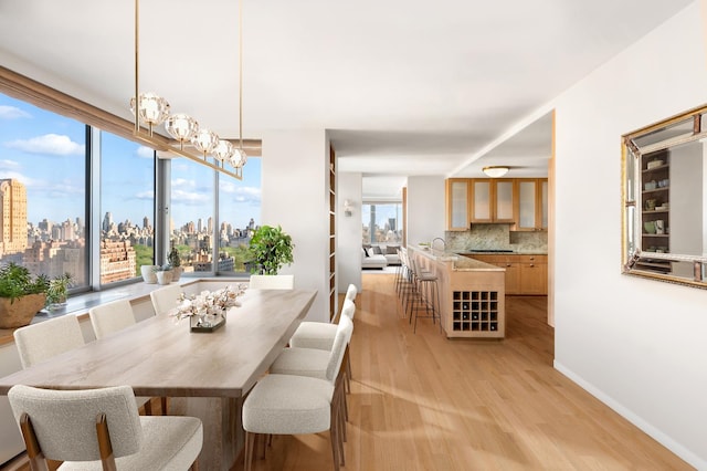 dining area with light wood-style flooring, a view of skyline, baseboards, and a chandelier