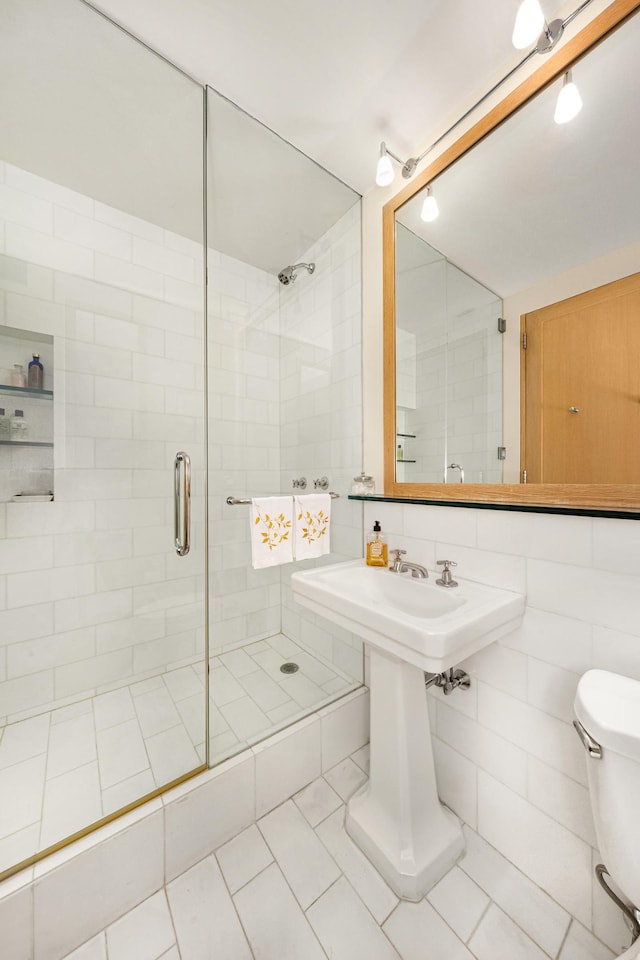 bathroom with a stall shower, toilet, and tile patterned floors