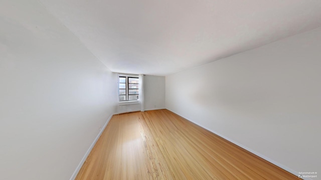 unfurnished room with light wood-style flooring and baseboards