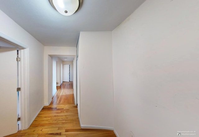 hallway featuring baseboards and light wood finished floors
