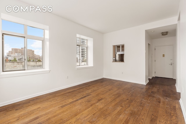 spare room with a wealth of natural light, wood finished floors, and baseboards