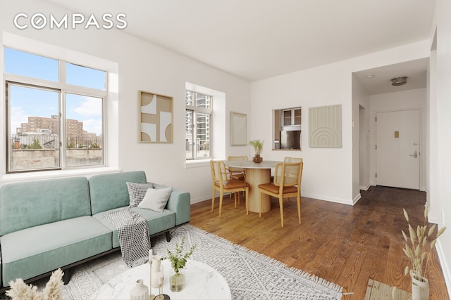 living area with a city view, baseboards, and wood finished floors