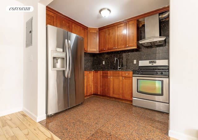 kitchen featuring tasteful backsplash, granite finish floor, appliances with stainless steel finishes, wall chimney range hood, and baseboards