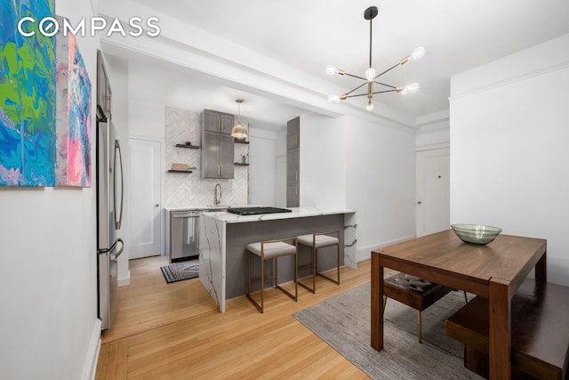 kitchen featuring a kitchen bar, decorative backsplash, light wood-style flooring, appliances with stainless steel finishes, and open shelves