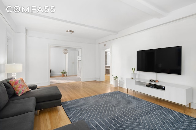 living area featuring beamed ceiling, wood finished floors, and baseboards