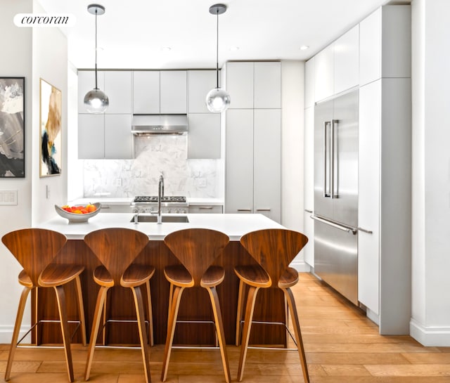 299 Riverside Dr Unit 3C, New York City, NY 10025 - kitchen featuring modern cabinets, range hood, stainless steel built in refrigerator, light wood finished floors, and a breakfast bar area