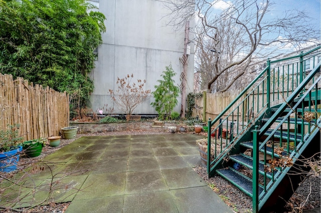 view of patio featuring stairway and fence