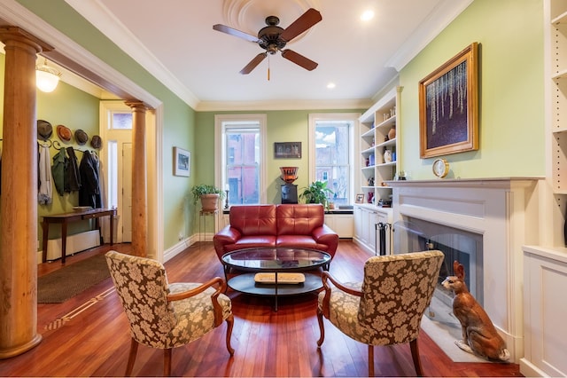 sitting room with wood-type flooring, ornamental molding, a fireplace, and ornate columns