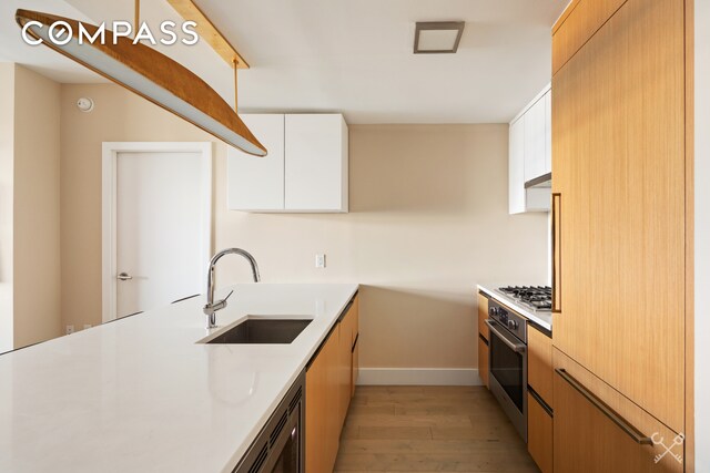 kitchen with a peninsula, a sink, light countertops, and white cabinets