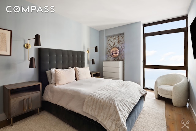 bedroom with light wood-style floors and floor to ceiling windows