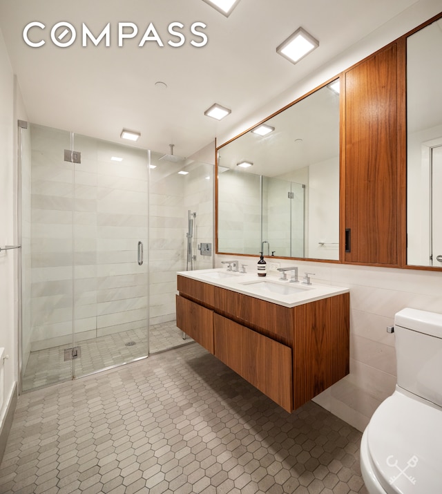 full bath featuring a stall shower, a sink, tile walls, and toilet