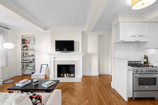 living room featuring baseboards, ornamental molding, a high end fireplace, and light wood-style floors