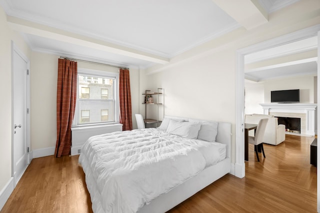 bedroom featuring beam ceiling, a fireplace, ornamental molding, wood finished floors, and baseboards