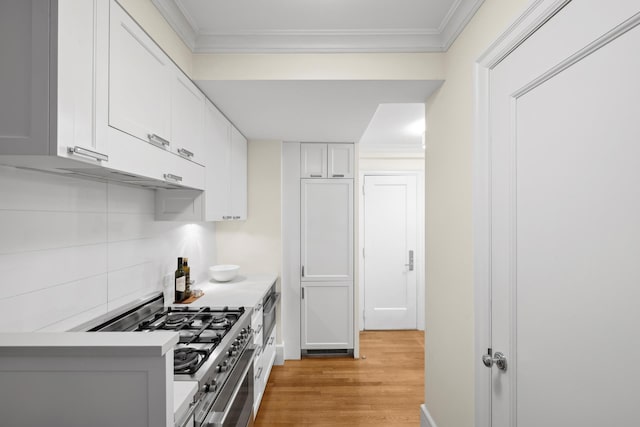 kitchen with white cabinetry, light countertops, ornamental molding, light wood finished floors, and stainless steel range with gas stovetop