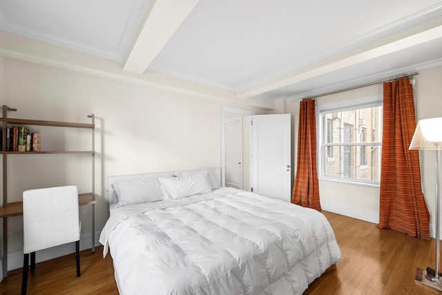 bedroom with ornamental molding, beam ceiling, and wood finished floors